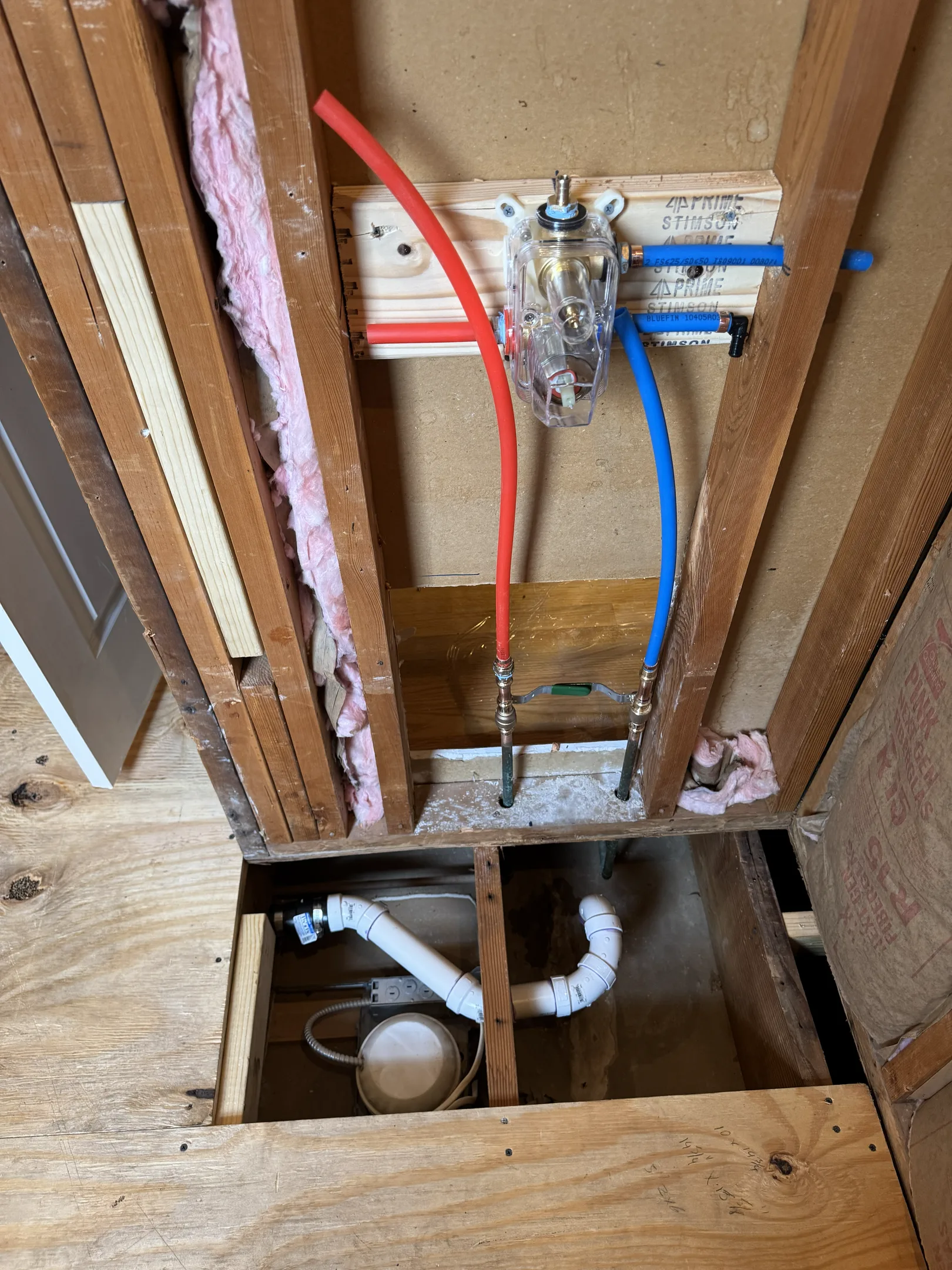 Bathroom floor framing with electrical wiring and plumbing lines visible