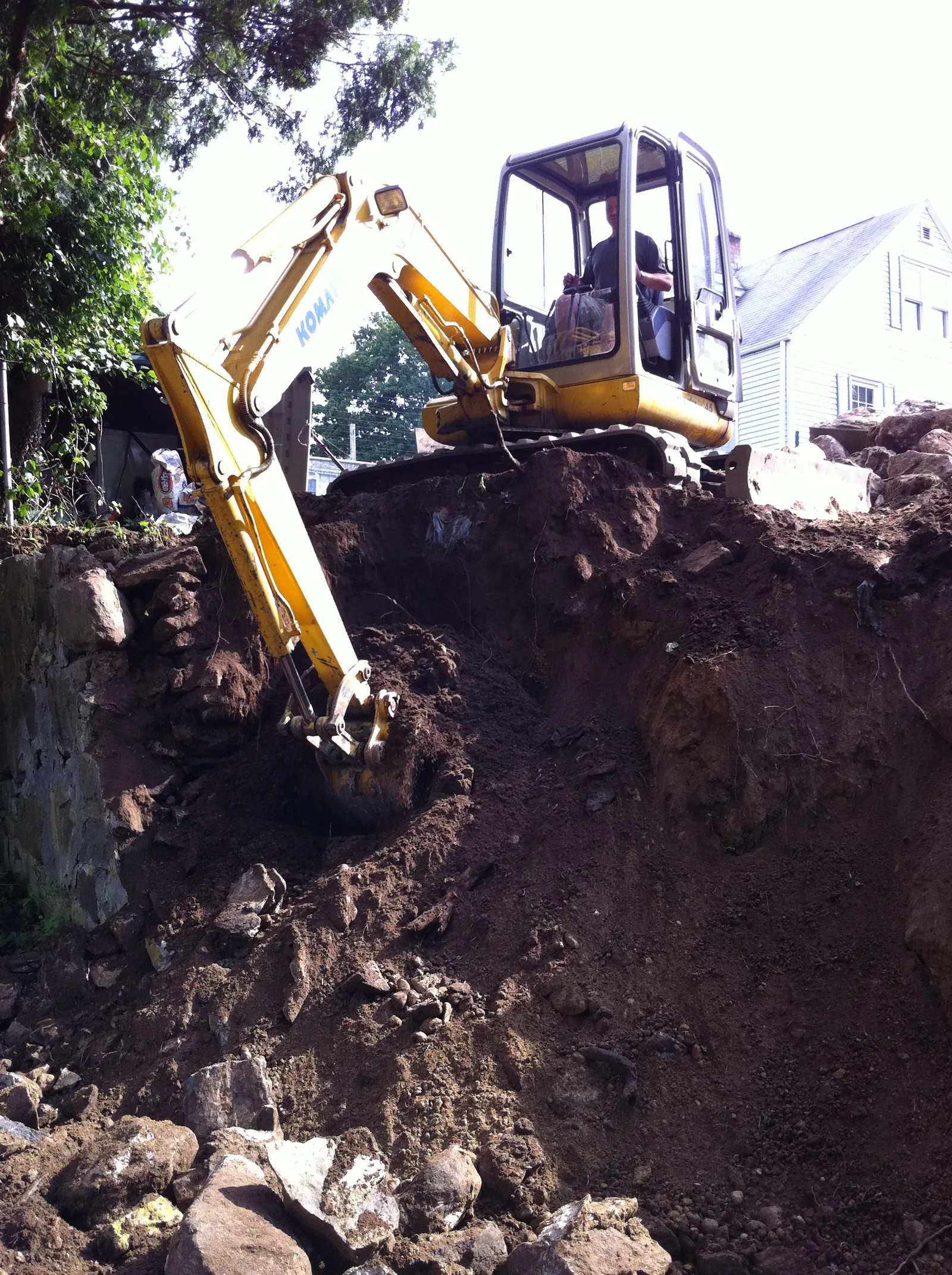 Excavator cutting back the slope during retaining wall reconstruction